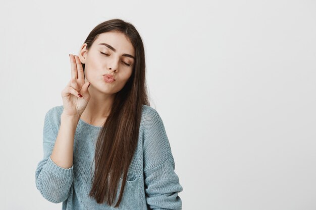 Silly cute woman show peace sign and blowing kiss