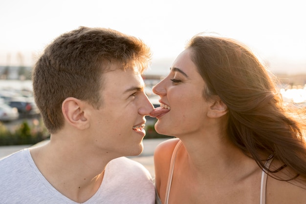 Silly girlfriend touching boyfriend's nose with her tongue