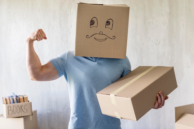 Free photo silly man with box over head showing bicep on moving day