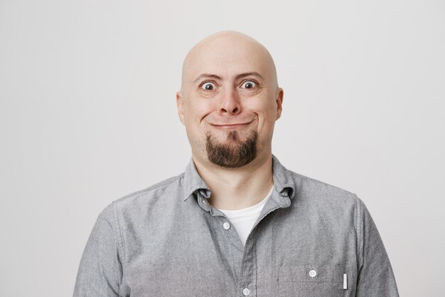 Silly middle-aged bald man with beard pulling scary smile