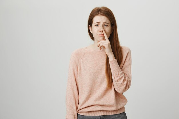 Silly redhead girl picking nose and looking sad