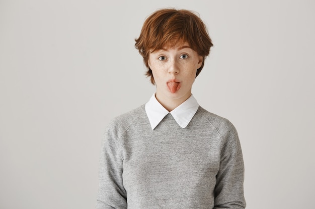 Redhead Girl with Short Haircut Posing Against White Wall