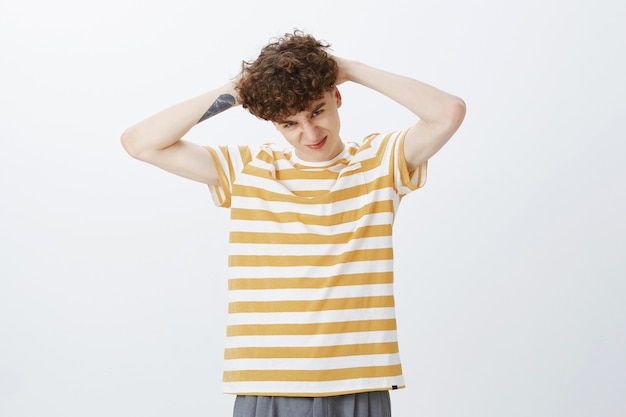 Silly teenage guy posing against the white wall