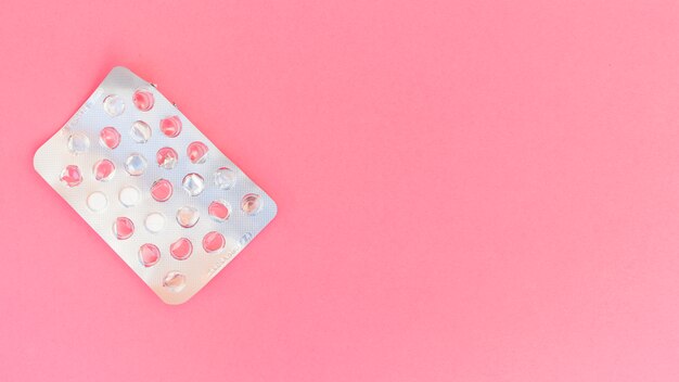 Серебряная блистерная упаковка таблеток на розовом фоне