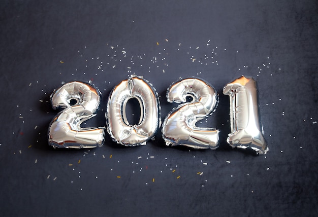 Free photo silver foil balloons made new years number on black background.