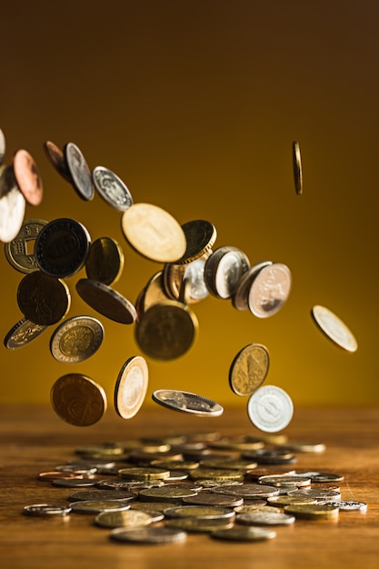 серебряные и золотые монеты и падающие монеты на деревянный стол