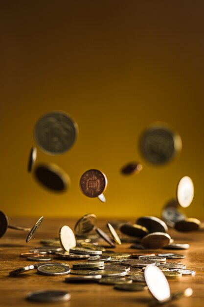 銀と黄金のコインと木製の壁に落ちるコイン