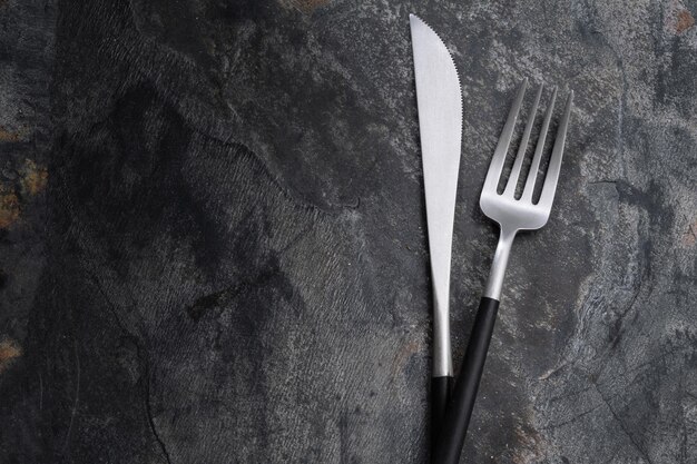 Silver modern cutlery on stone background. Closeup