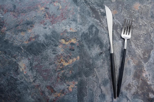 Silver modern cutlery on stone background. Closeup
