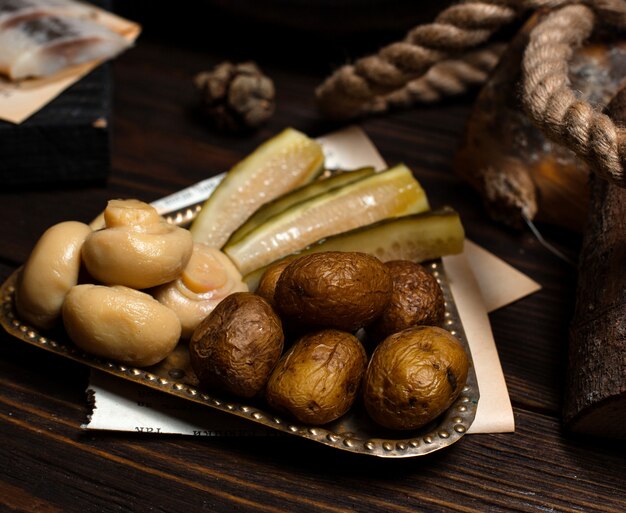Silver plate of pickled mushrooms, cucumbers and baked potatoes