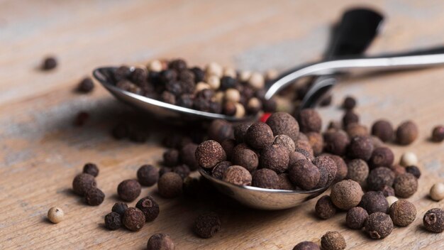 Silver spoon with peppercorns on table