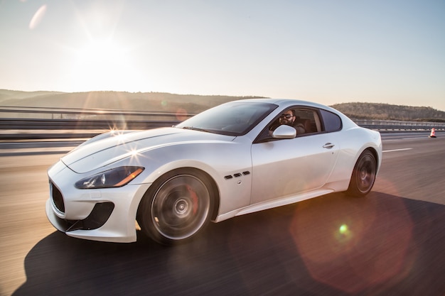 Silver sport car with a driver on the highway.