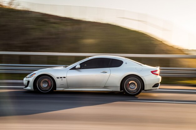 A silver sport coupe driving in the highway.