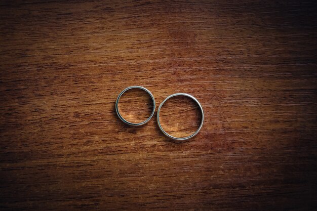 Silver wedding rings lie on the wooden table