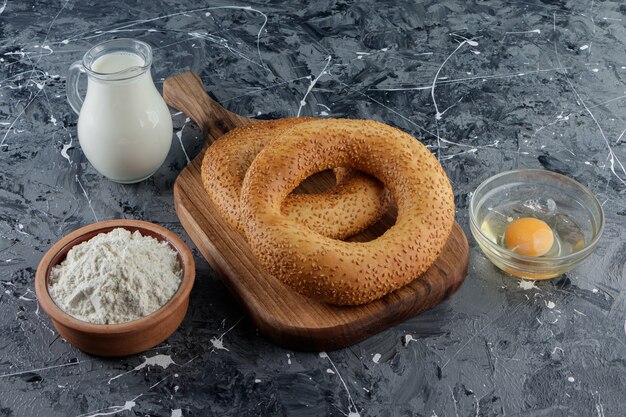 Simit with sesame seeds and a glass bowl of flour with uncooked chicken egg