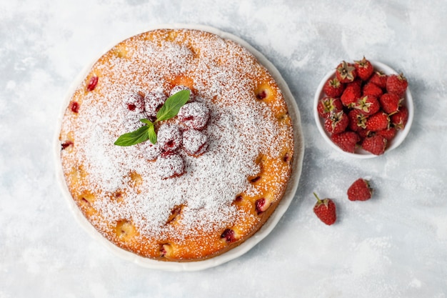 Simple cake with powdered sugar and fresh raspberries on a light . Summer berry dessert.