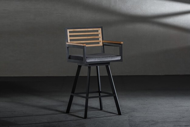 회색 벽이있는 방에 금속 높은 다리가있는 단순한 의자