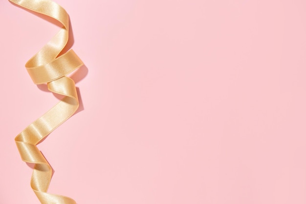 Free photo simple golden ribbon on pink background