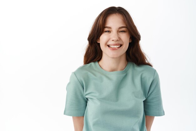 Sincere and candid people Beautiful girl laughing smiling broadly and squinting at camera standing joyful against white background Copy space