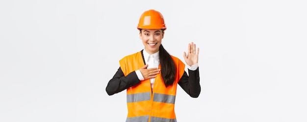 Free photo sincere honest and confident asian female engineer at building area making promise give oath to clients looking trustworthy standing in safety helmet telling truth white background