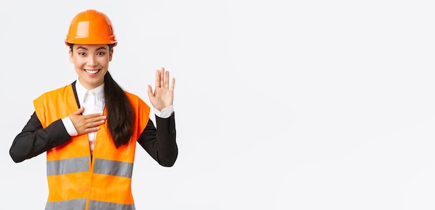 真摯に正直で自信を持って建築エリアでアジアの女性エンジニアが約束をしていることは、真実の白い背景を伝える安全ヘルメットに信頼できる立っているように見えるクライアントに誓いを立てます