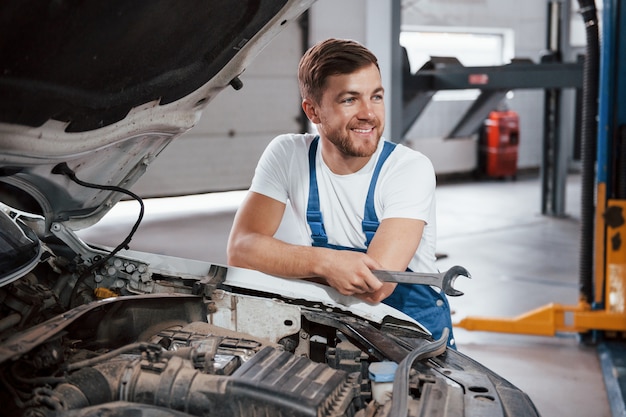 Sincere smile. Employee in the blue colored uniform works in the automobile salon