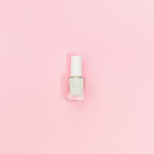 Single bottle of white nail polish on pink background