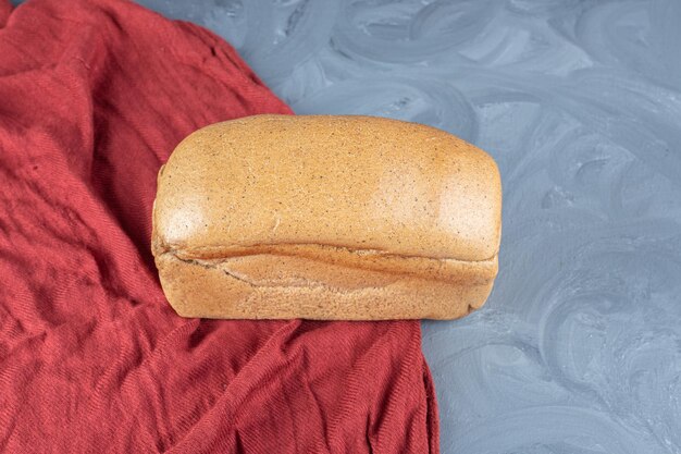 無料写真 大理石の表面の赤いテーブルクロスの上の単一のパン。