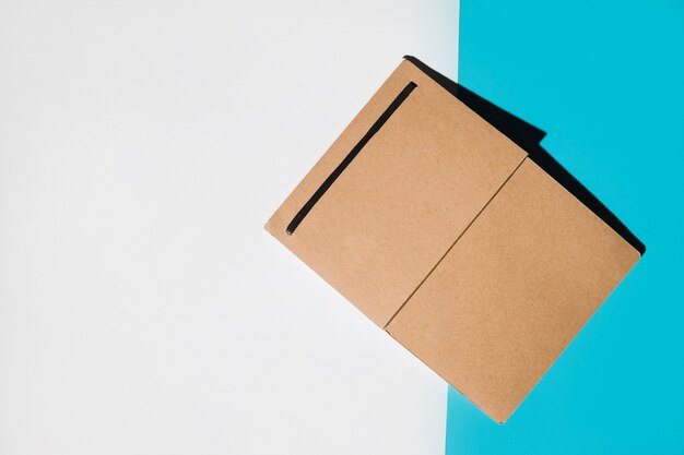 Single brown cover notebook on white and blue backdrop
