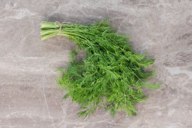 Single bundle of dill on marble.