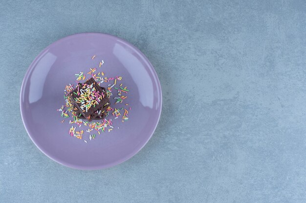 Бесплатное фото Одинарные шоколадные вафли с посыпкой на фиолетовой тарелке.