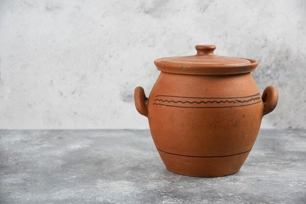 Одинарная глиняная антикварная ваза на мраморной поверхности.