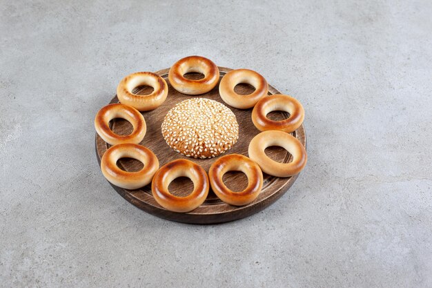 single cookie surrounded by sushki on a wooden board on marble surface.