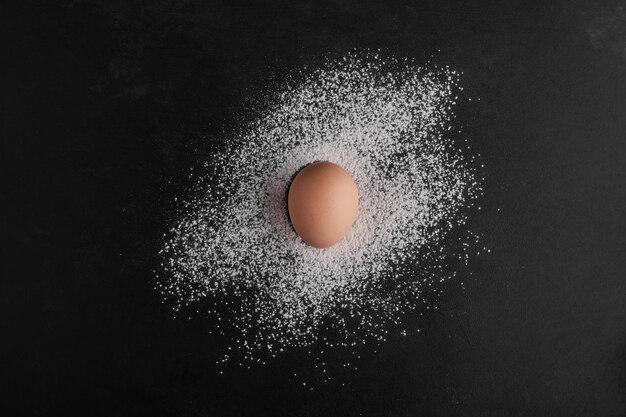小麦粉スペースの中央にある単一の卵、上面図。