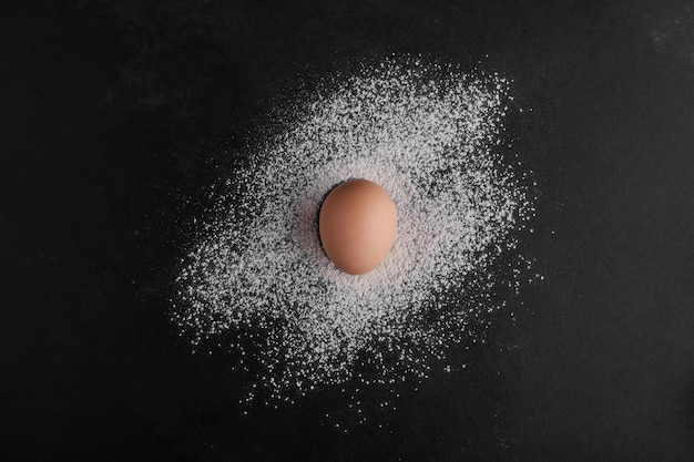 小麦粉スペースの中央にある単一の卵、上面図。
