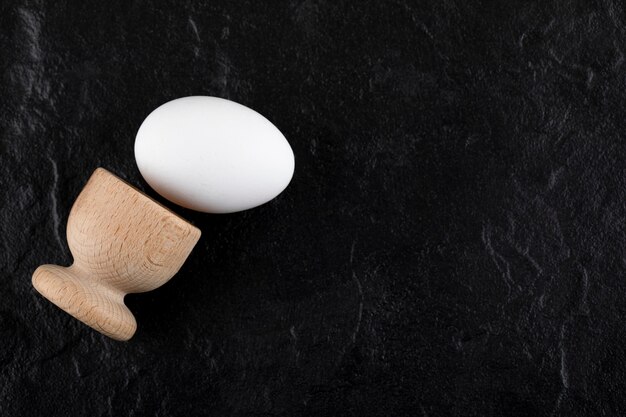 Single egg and wooden box on black surface. 