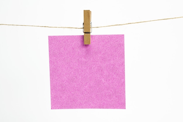 Single empty paper sheet for notes that hang on a rope with clothespins and isolated on white.