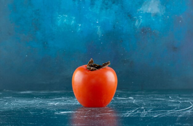 大理石のテーブルの上の単一の新鮮な柿。