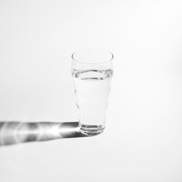 Free photo single glass of water with bright shadow isolated on white background