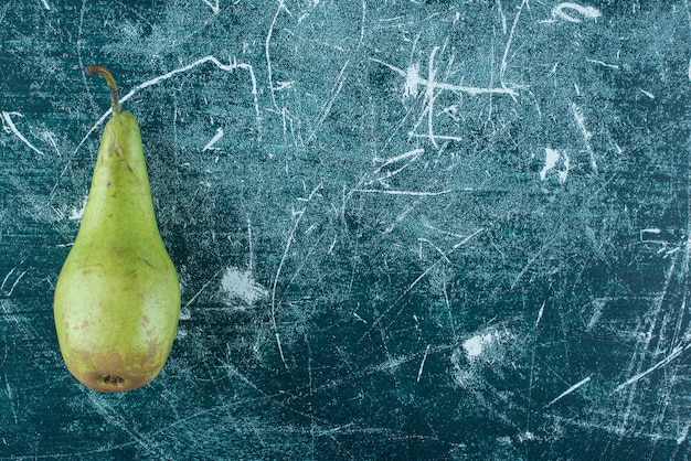 Free photo single green pear on marble table.