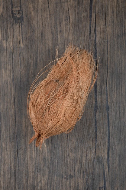 Single hairy hard coconut on wooden surface