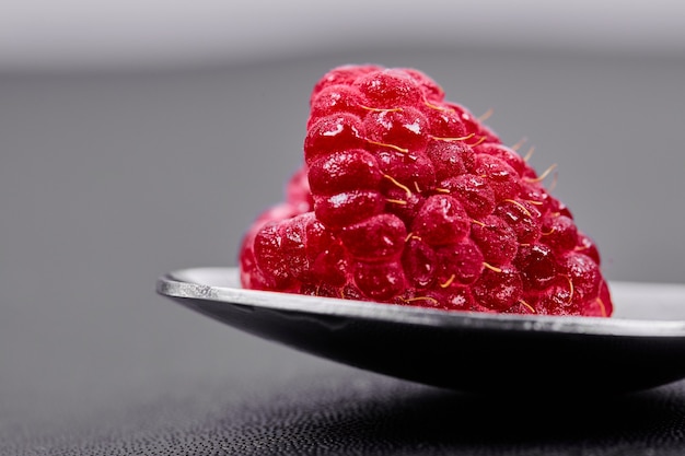 Single large raspberry on spoon. Close up. 