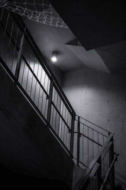 Single light bulb illuminating interior dark staircase