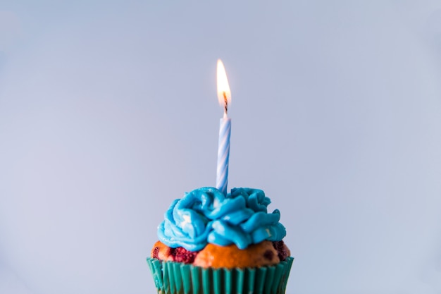 파란색 배경 컵 케이크 위에 단일 조명 촛불