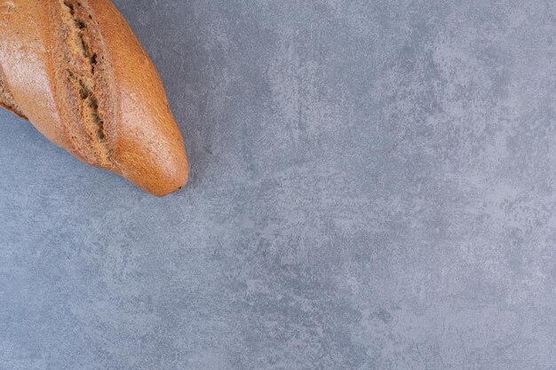 Single loaf of baton bread on marble background. High quality photo