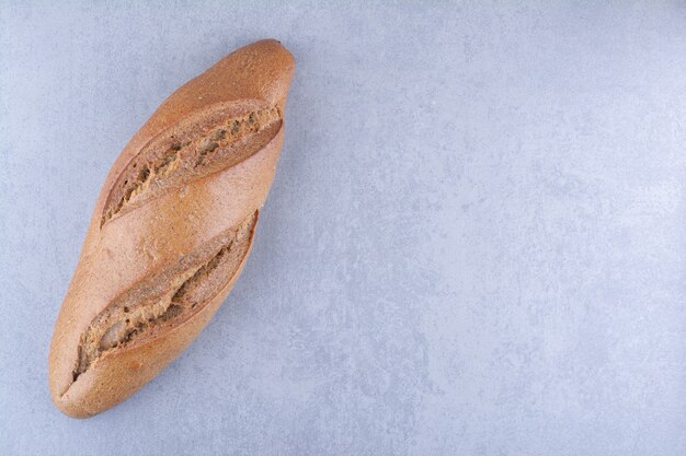 Single loaf of baton bread on marble surface