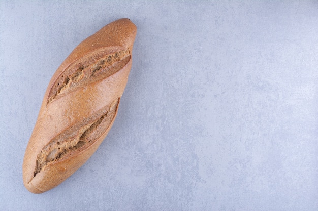 Single loaf of baton bread on marble surface