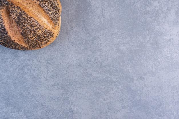 Буханка хлеба, покрытого черным кунжутом, на мраморе.