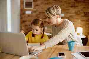 免费照片单身母亲和女儿在家教育时使用笔记本电脑