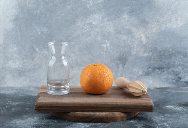 Одиночный апельсин, развертка и стекло на деревянной доске.